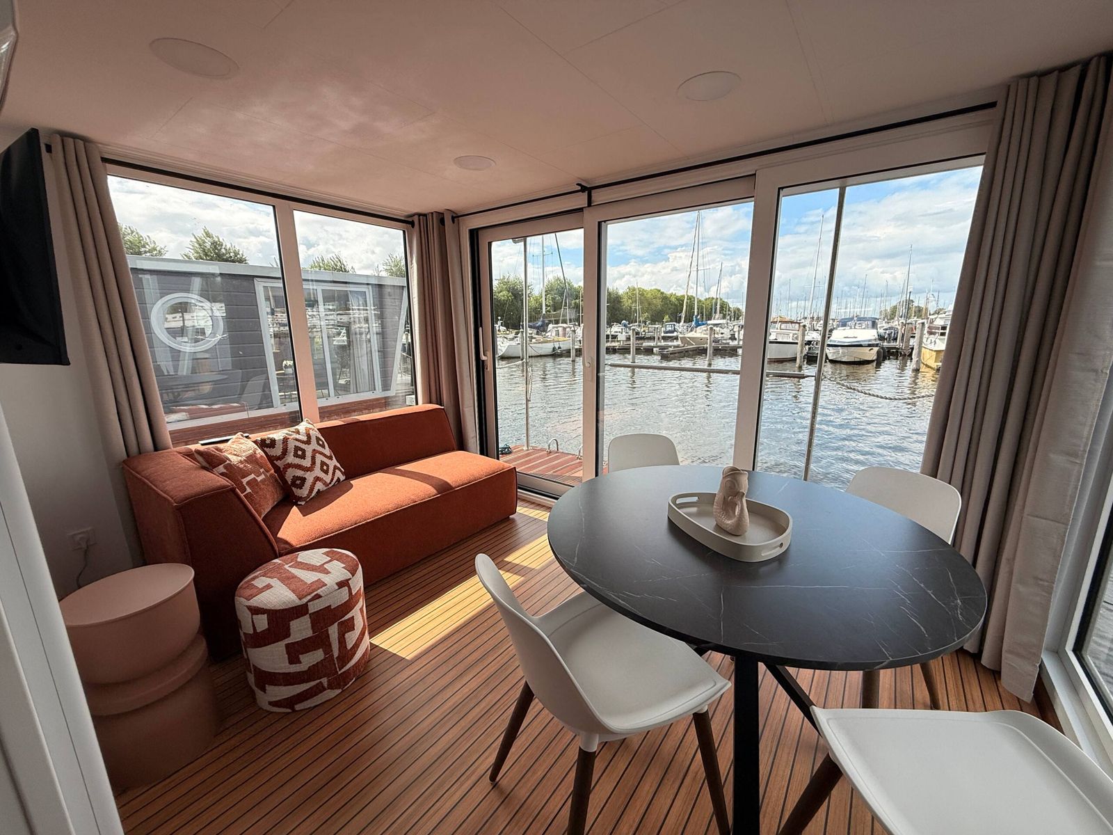 Wohnzimmer des Glamping-Hausboots mit Blick auf den Hafen