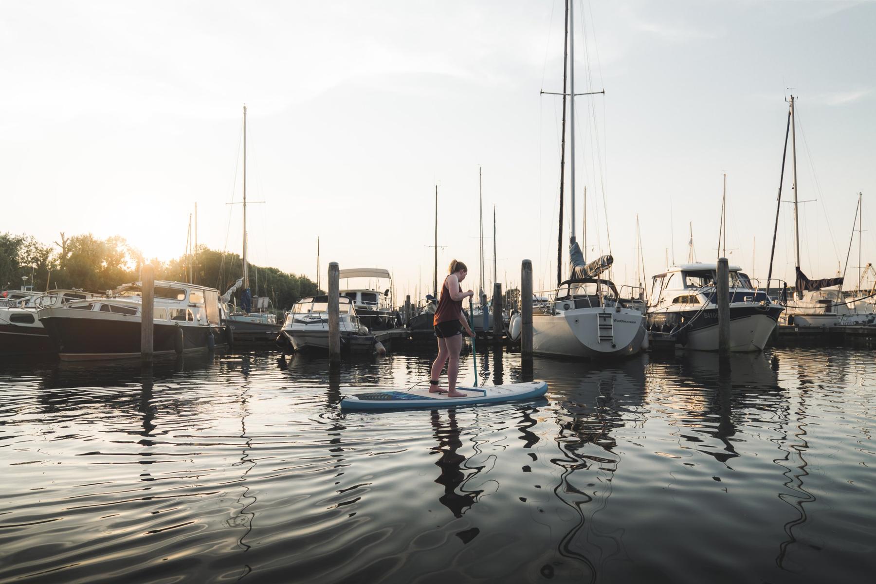 SUP'en in de haven bij zonsondergang